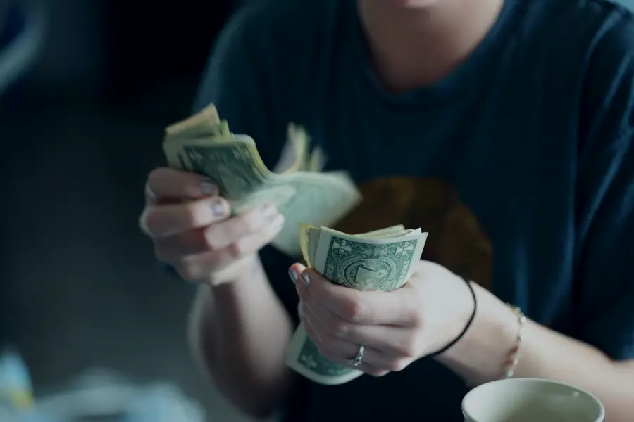 Hands counting a stack of dollar bills.